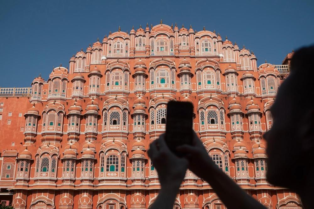 Silhouette of man photographing palace Hawa Mahal in old part of Jaipur also know as Pink City.