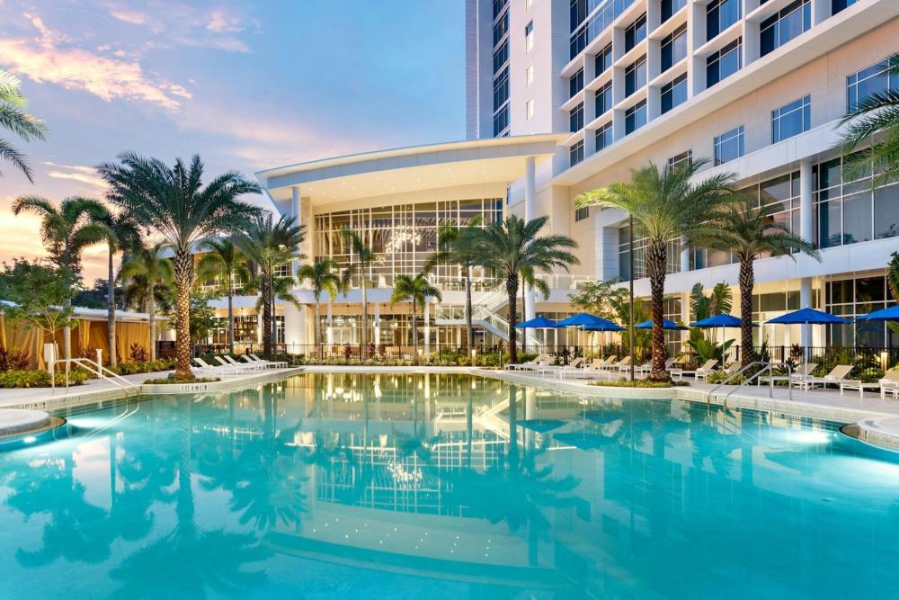 The pool area at the JW Marriott Orlando Bonnet Creek Resort & Spa, featuring lounge chairs and palm trees under a clear blue sky