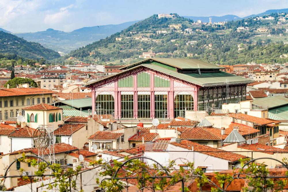 A cityscape featuring numerous buildings with a mountain backdrop, highlighting Mercato Centrale in San Lorenzo