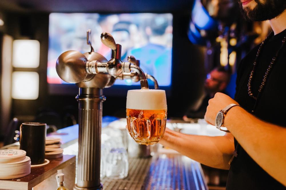 A person pours beer into a glass at a bustling sports bar in New York City