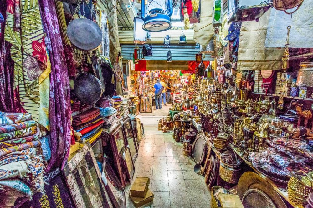 A bustling souk with shoppers exploring various items and vibrant displays