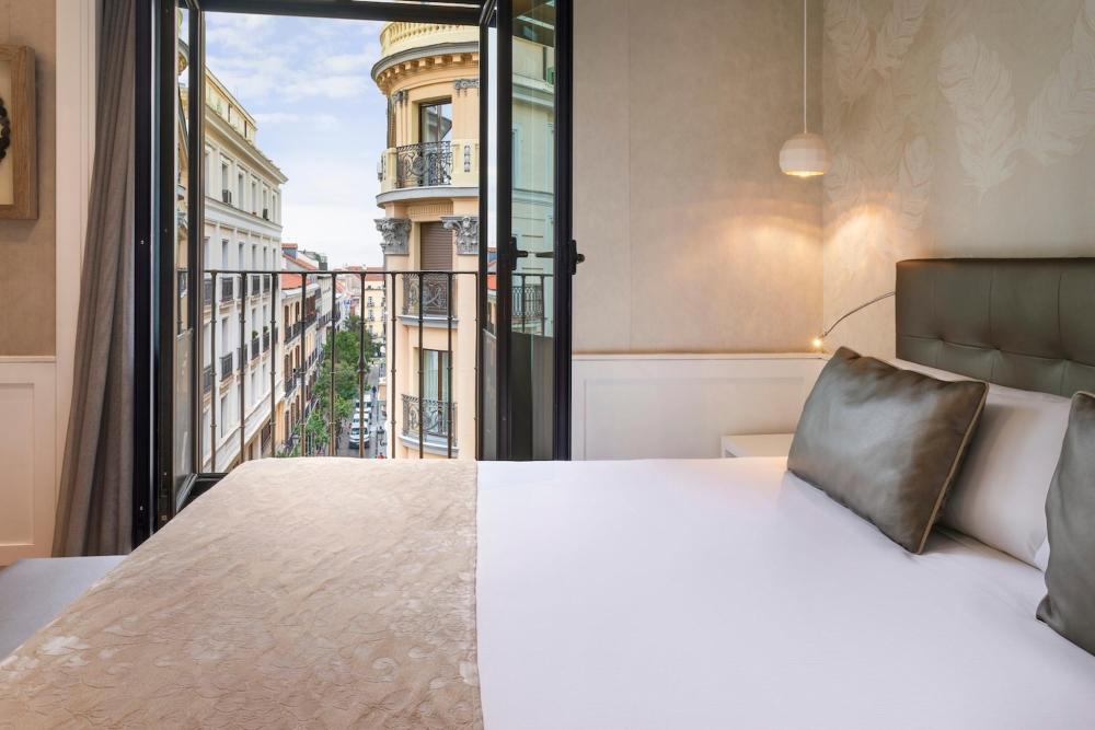 A cosy bedroom with a balcony offering a view of Madrid's city skyline, located in Catalonia Puerta del Sol