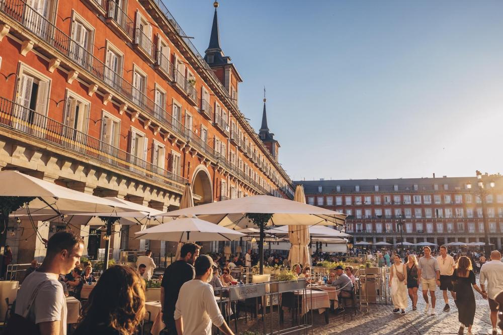 People stroll through Plaza Mayor in central Madrid, surrounded by historic architecture and vibrant atmosphere
