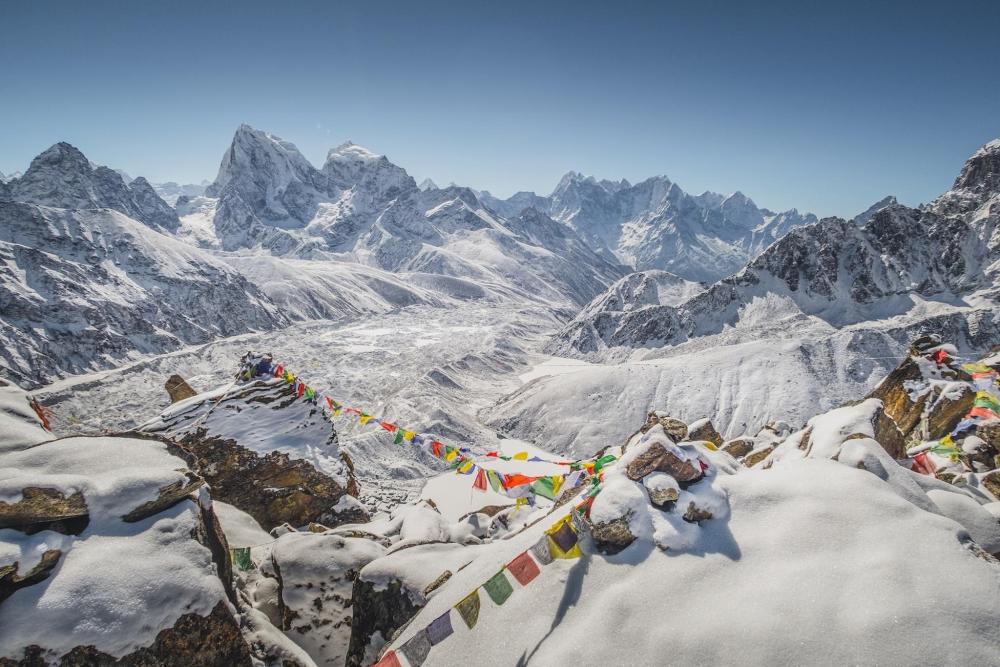 Panoramic view from Mount Everest, featuring snow-capped mountains under a bright blue sky