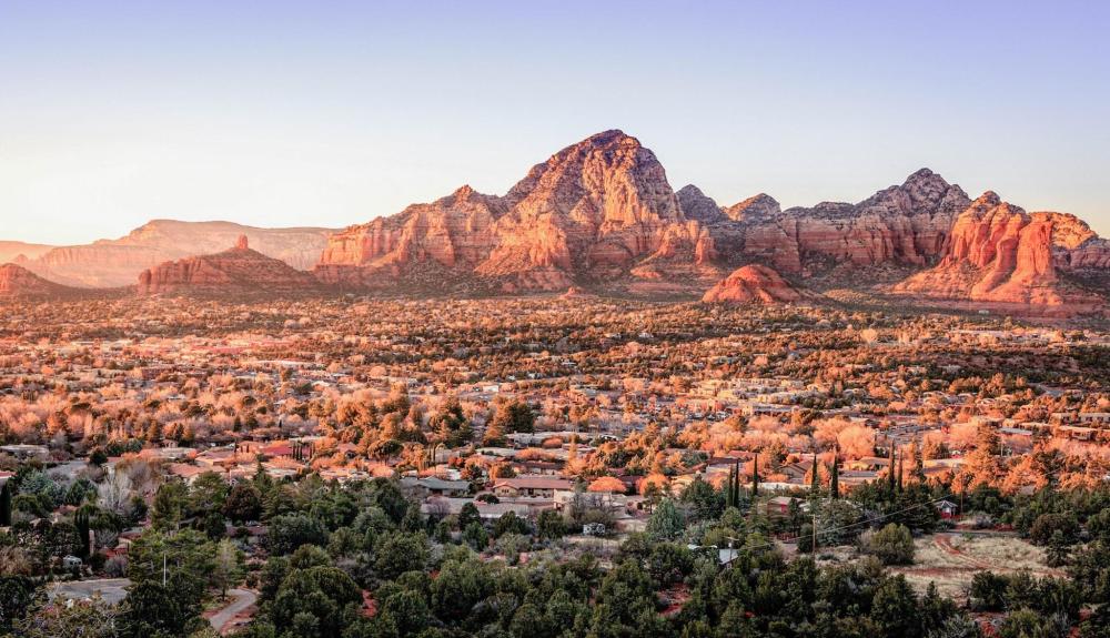 Sunset over the red rocks of Sedona, Arizona, casting warm hues across the rugged landscape – perfect for a Friendsgiving getaway