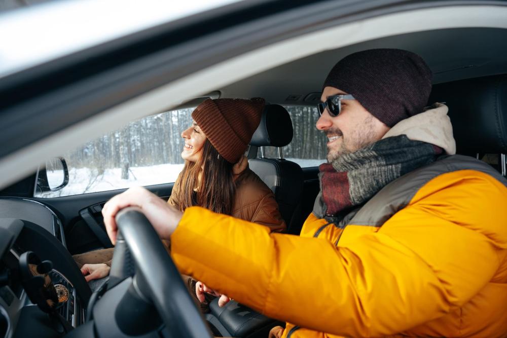 A man and woman in winter attire drive a car along an alternate route for Thanksgiving.