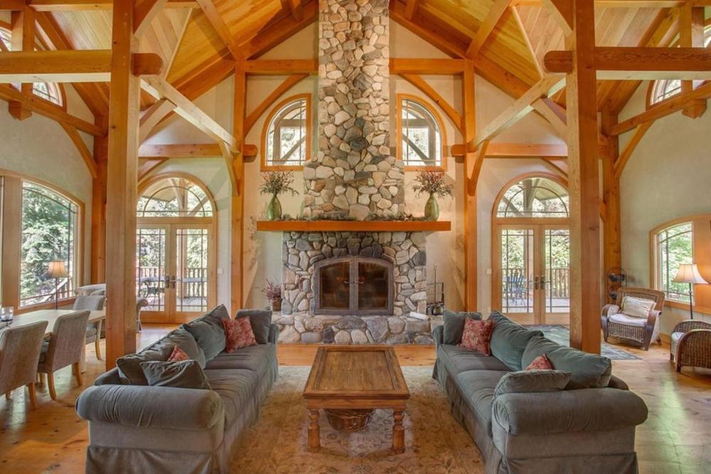 A spacious living room at Snowgrass Lodge featuring a cozy stone fireplace as the focal point.