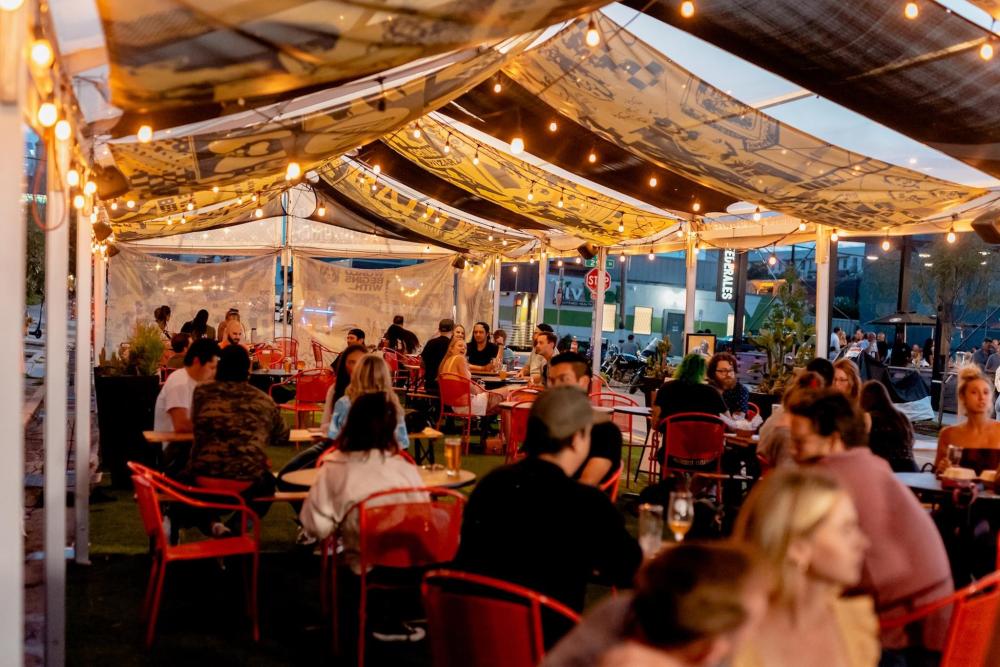 A group of people seated at tables under a canopy in the River North Art District, enjoying a social gathering