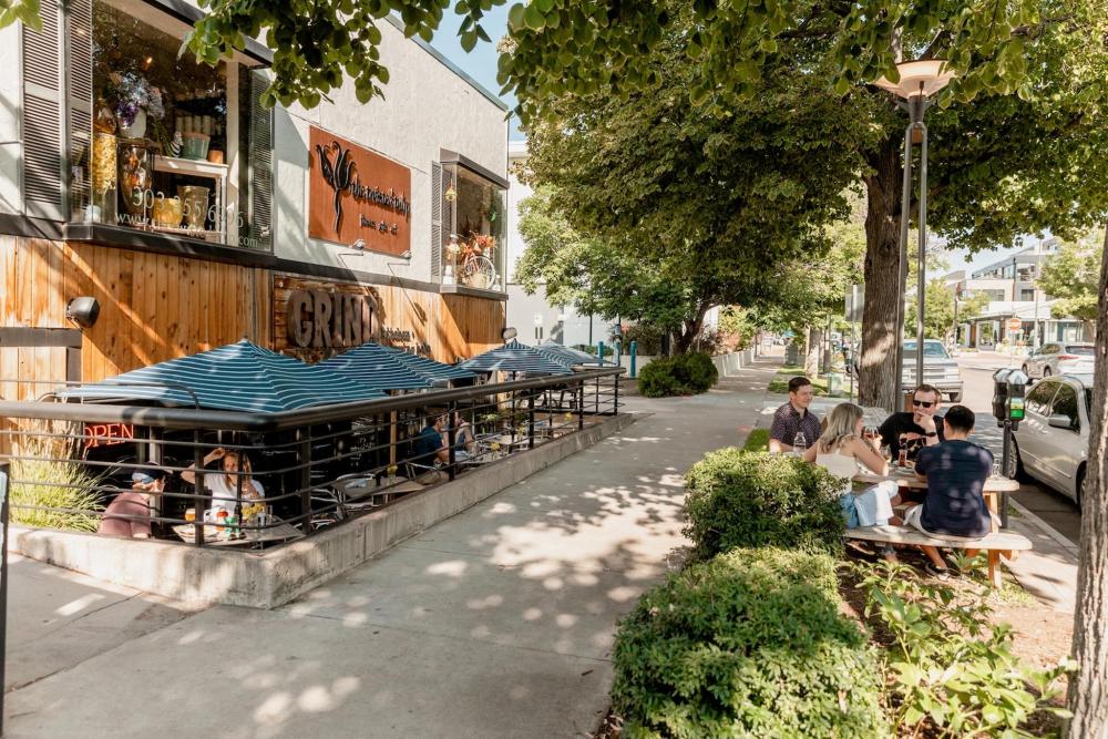 People dine at outdoor tables on a sidewalk outside a restaurant in Cherry Creek