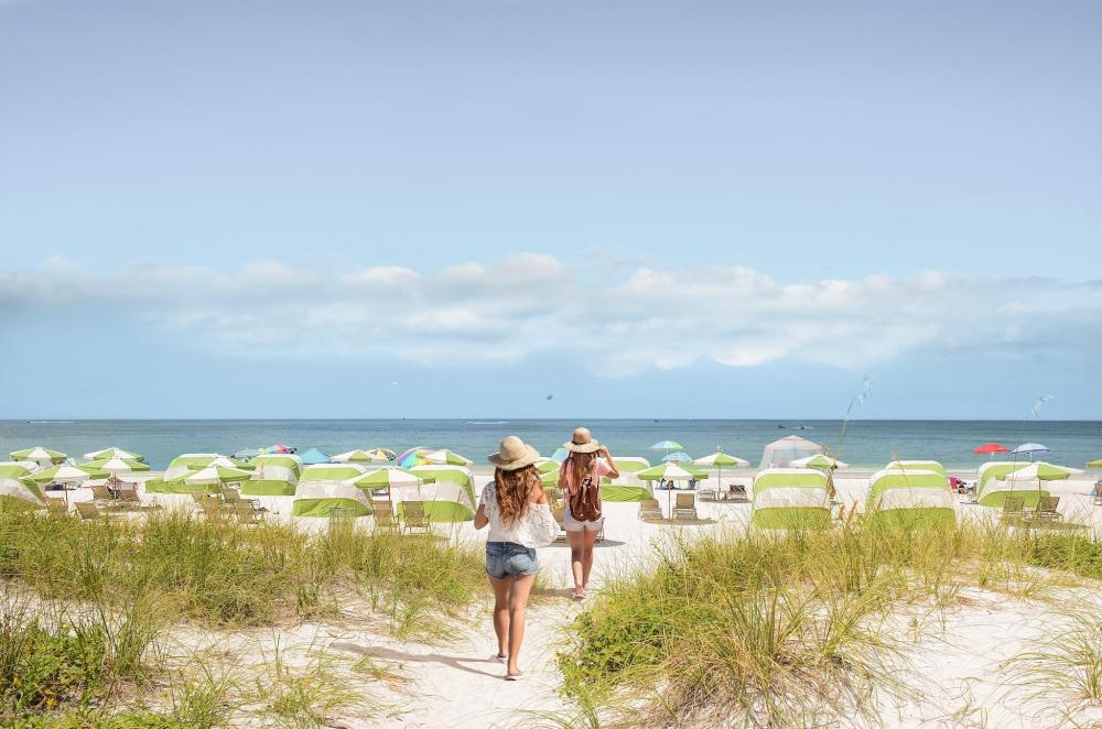 Two people walk together on Clearwater Beach, Florida, with waves gently lapping at the shore.