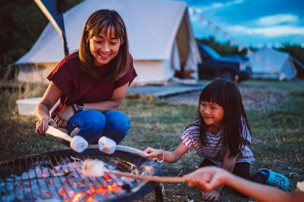 Children gathered around a campfire, roasting marshmallows.