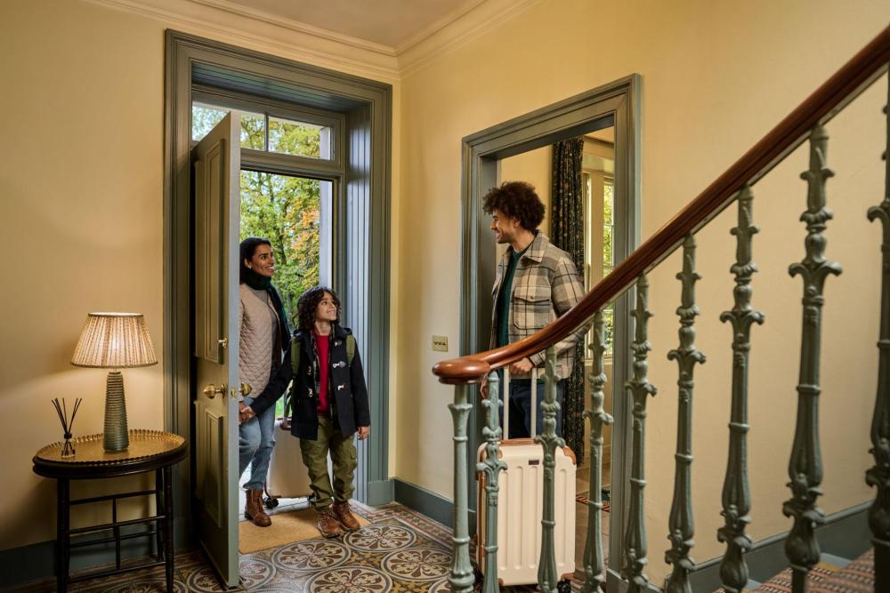 A family of four stands in front of a duplex door, looking happy and engaged with each other.