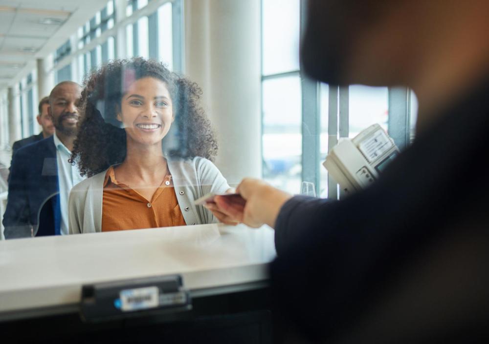 Passenger hands passport to airport staff at check-in desk