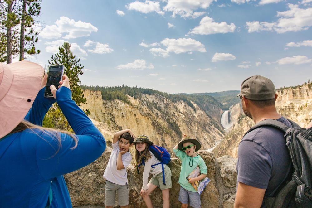Children posing at Yellowstone National Park, sticking their tongues out, with their hands above their heads