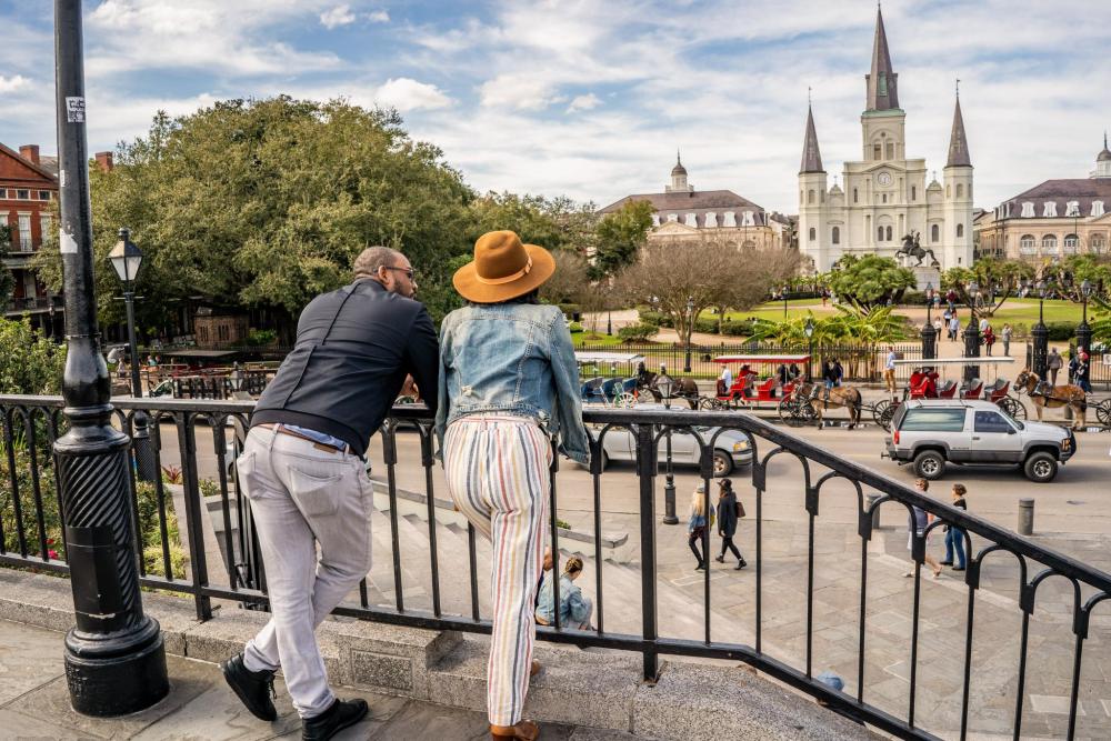 A couple look out to Jackson Square, as they stand by some railing