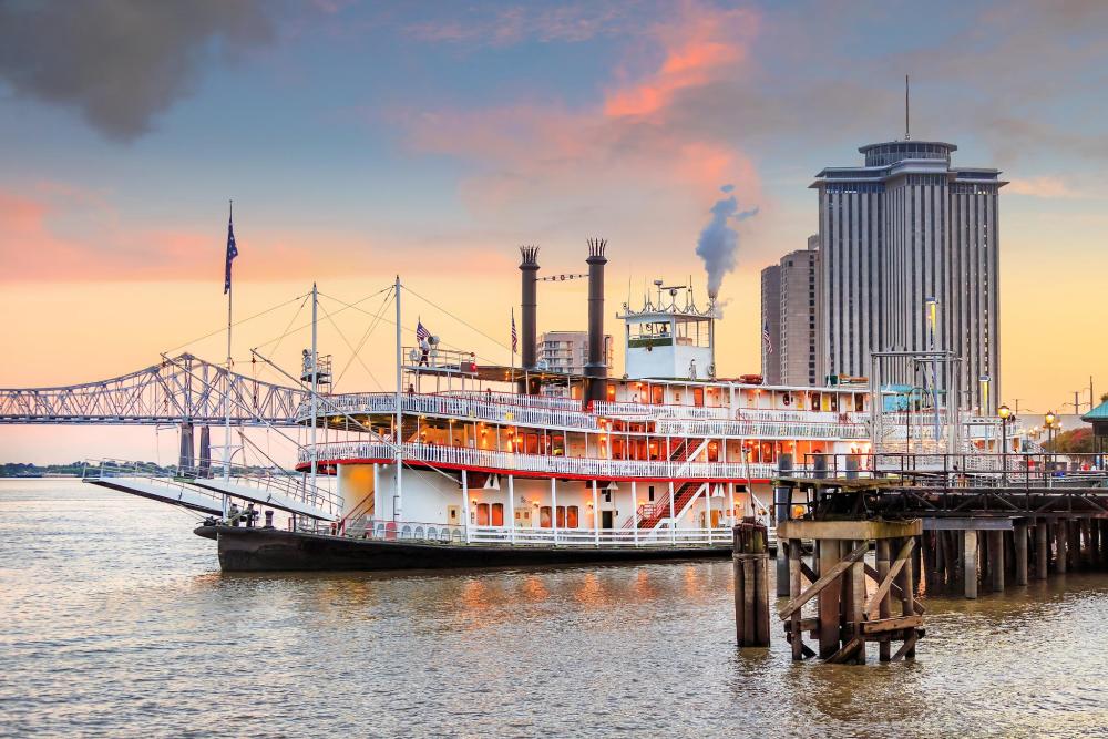 Steamboat Natchez gliding on the water, showcasing its classic design and vibrant colours against the river backdrop.