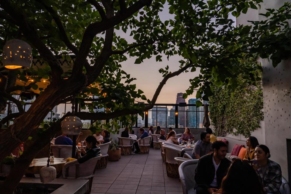 Guests seated at an open-air rooftop restaurant with views across Los Angeles