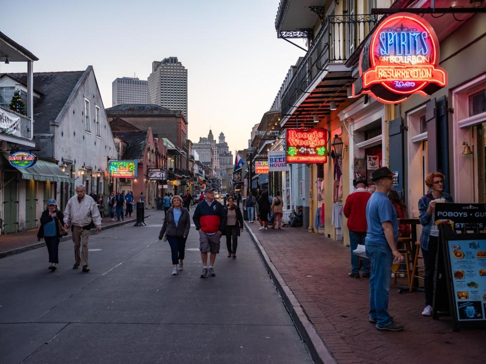 A New Orleans street with people walking and standing, showcasing the city's nightlife 