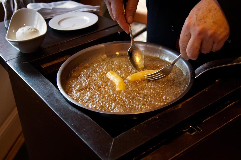 A cook prepares gumbo in a pan, with bubbles rising and ingredients visible on the countertop.