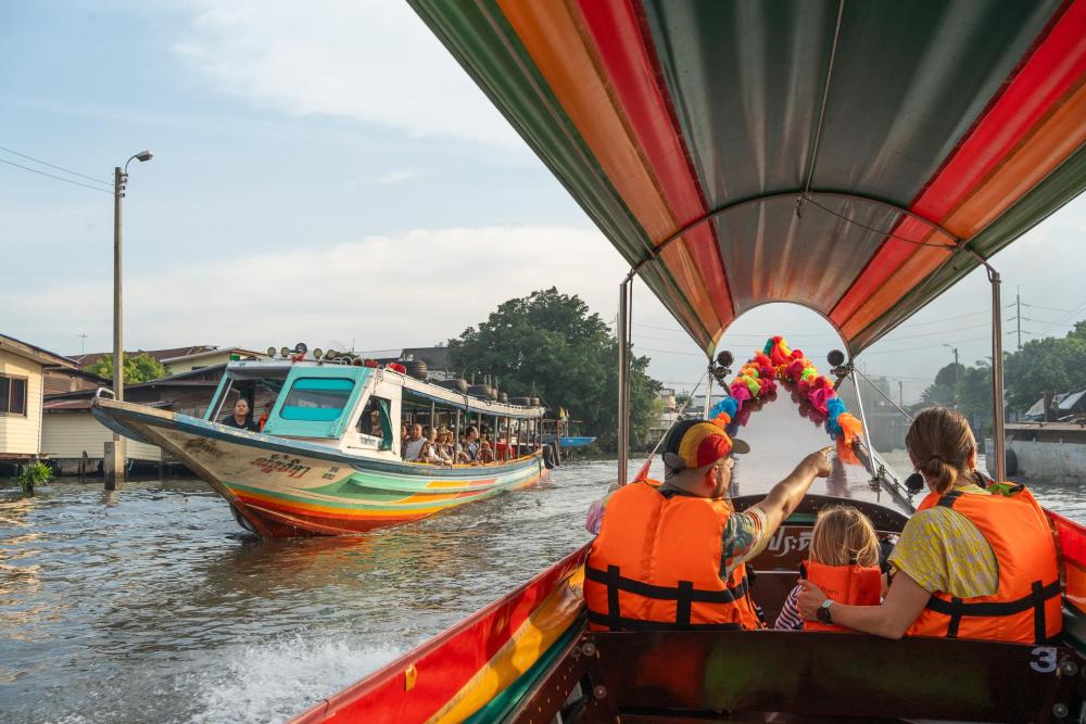 Tourists riding a longtail boat along a Bangkok canal