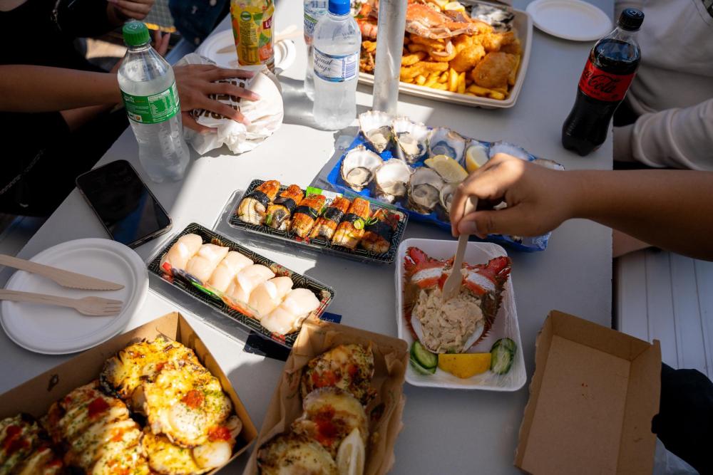 Shared seafood and sushi dishes on an outdoor table