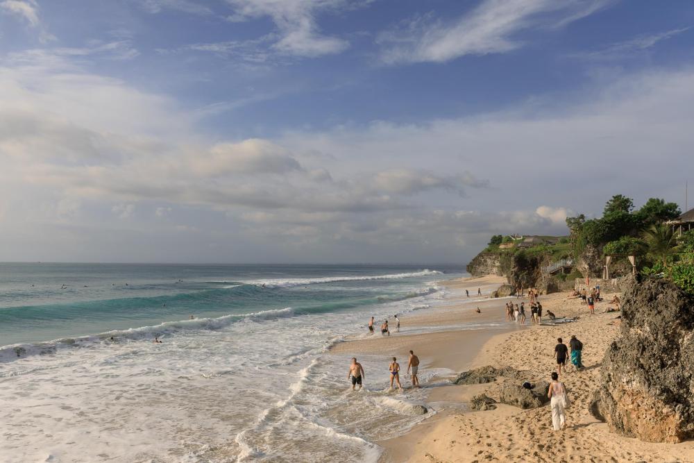 People walking and surfing on a sandy Bali beach