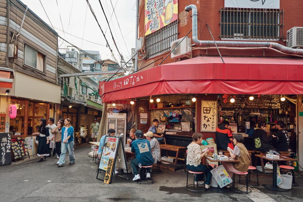 People eating at a busy outdoor restaurant in Osaka