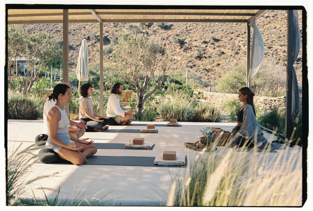 People taking part in an outdoor yoga class surrounded by hills