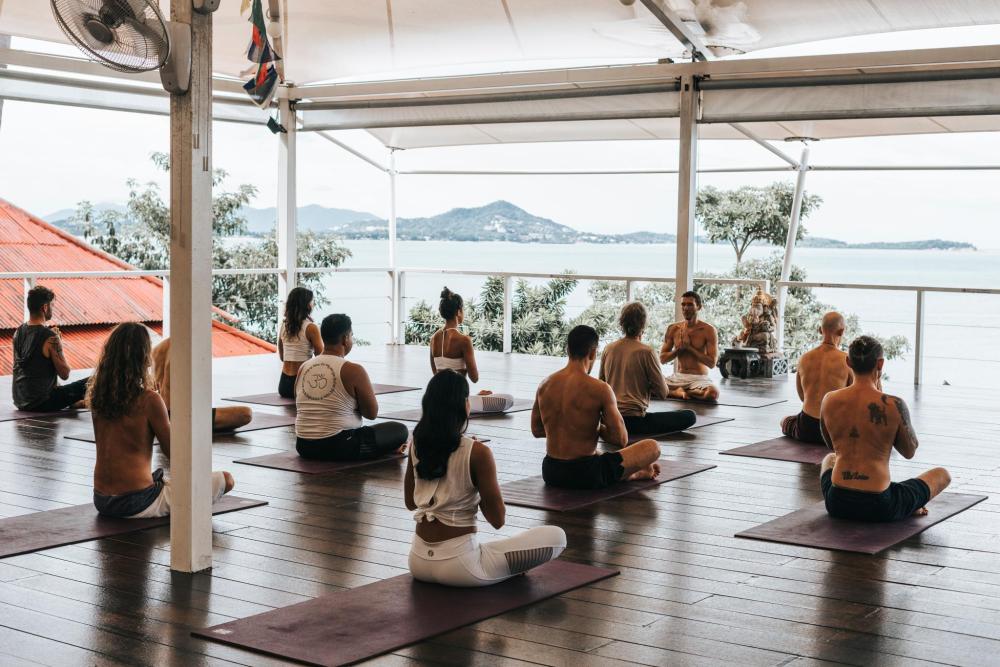 Group taking part in a yoga class overlooking the sea and hills