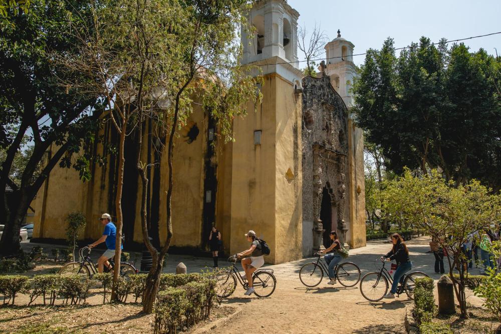 A family bikes past Capilla de la Inmaculada Concepción in Mexico City
