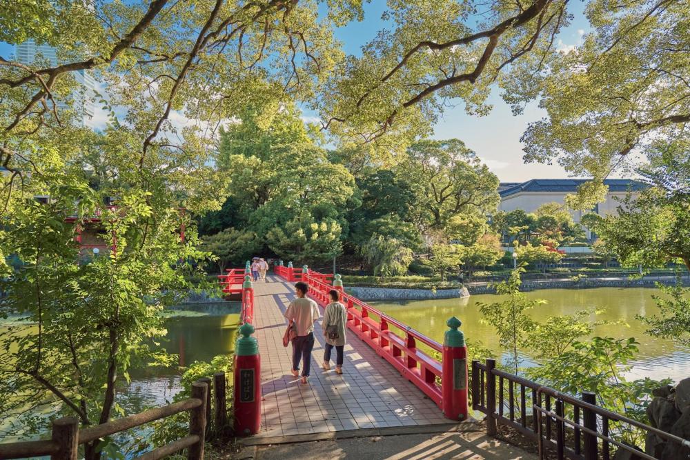 A couple of people stroll across a bridge in Osaka over a river