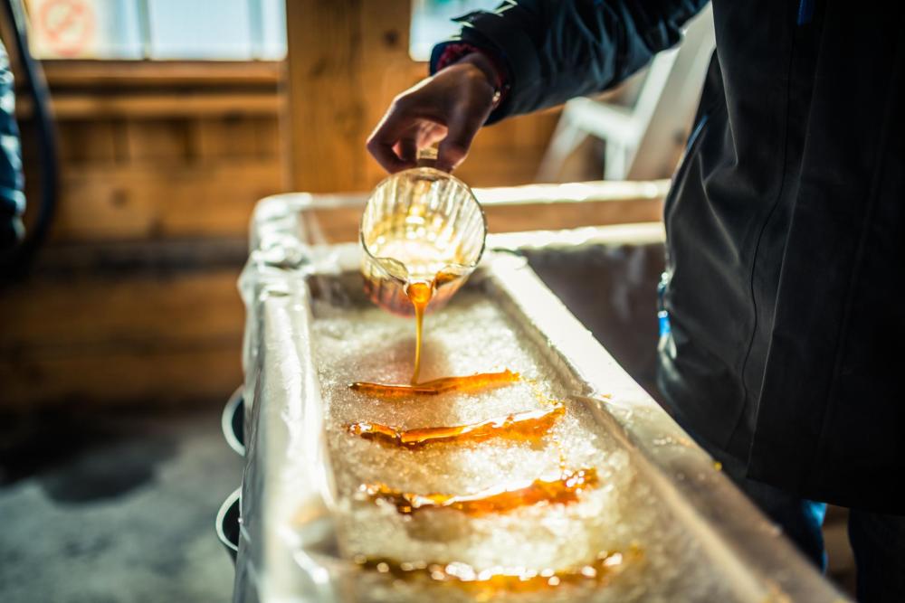 Someone takes part in the Canadian culinary experience of making maple taffy, known as tire sur la neige in French