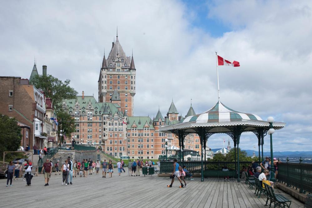 A view of Rue Saint-Louis in Old Quebec featuring historic stone buildings, shops, and a view of the Château Frontenac in the distance.