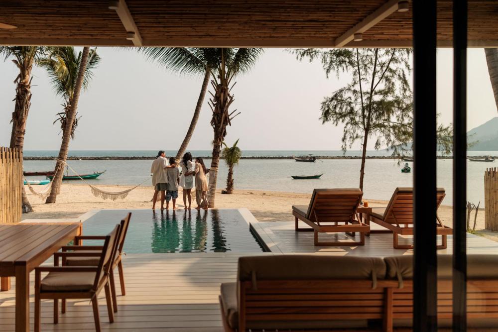 A family on the beach next to a pool, enjoying a sunny tropical vacation