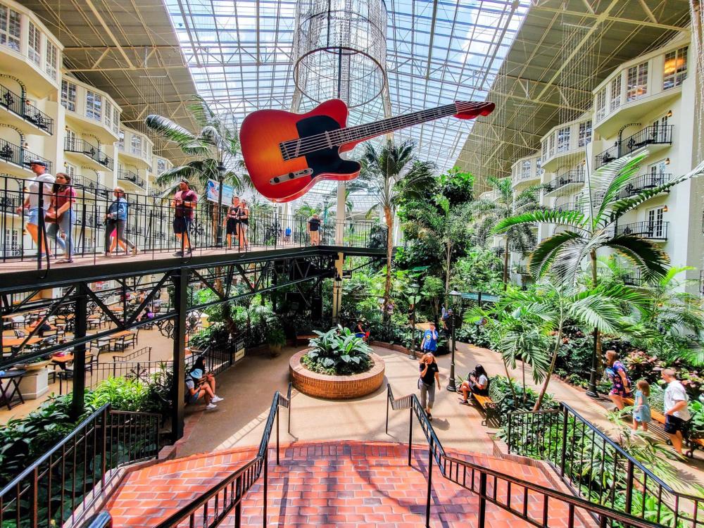 Eine elegante Gitarre, die im Atrium eines Hotels hängt und ihr Design vor dem Hintergrund moderner Architektur präsentiert.