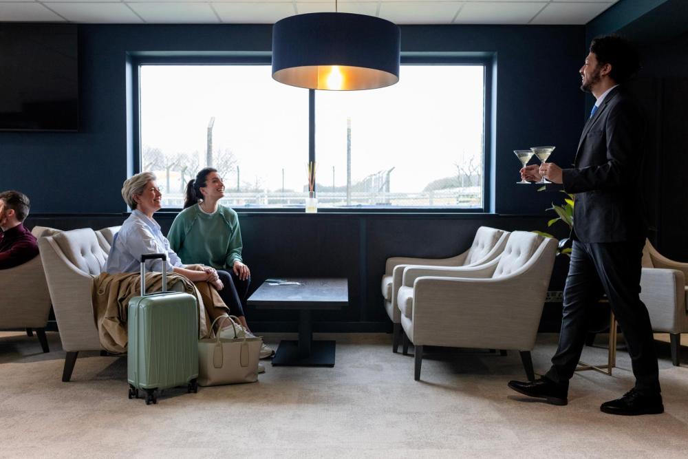 Plusieurs personnes attendent assises, échangeant des regards et une conversation dans une salle d'attente