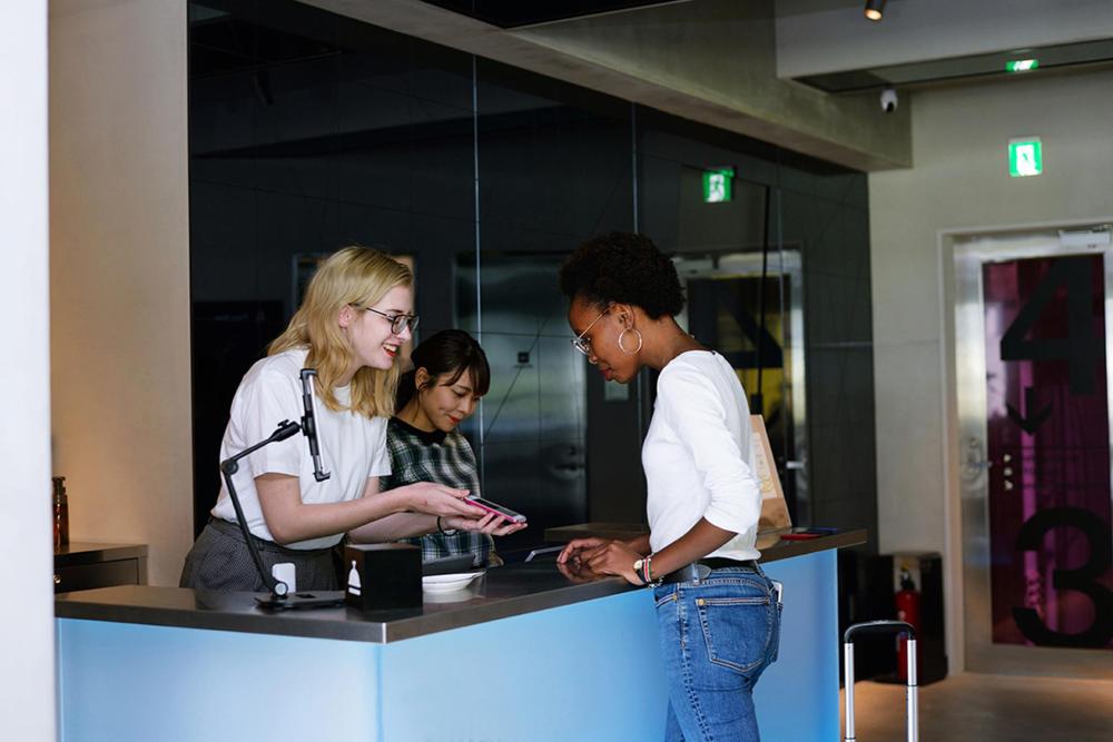 Two women are interacting at a front desk, likely involved in a discussion or transaction