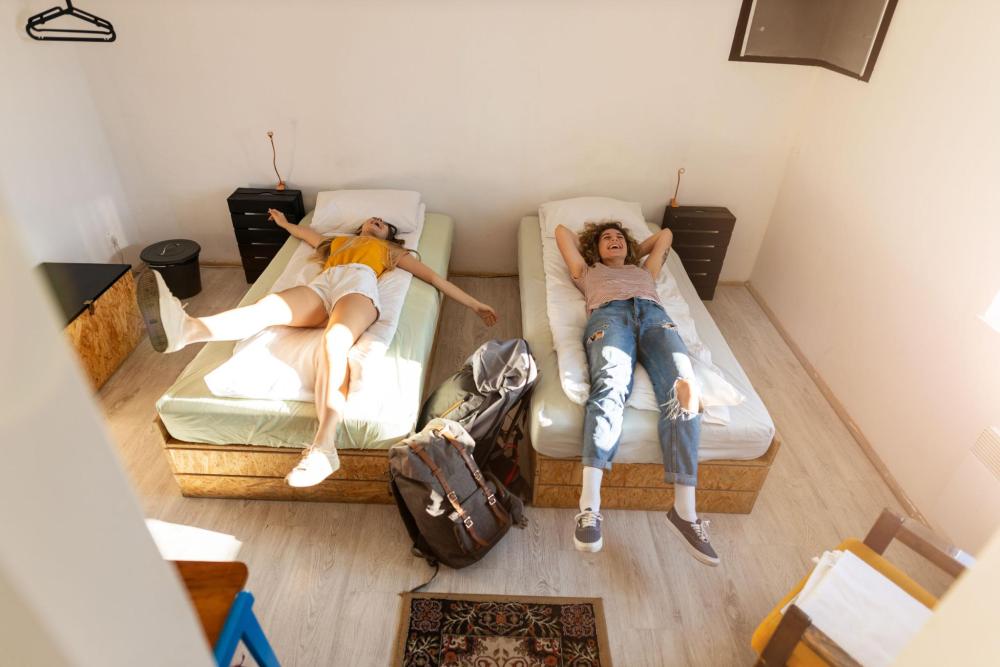 two girls laughing while on their bed at a minimalistic hostel room