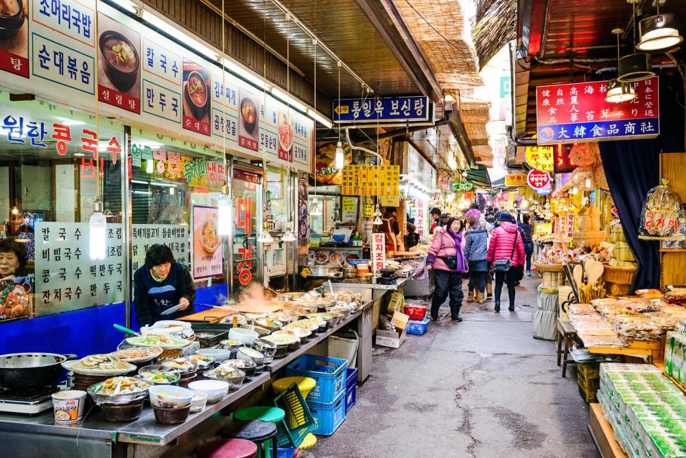 Visitors browse food stalls in a bustling Seoul market