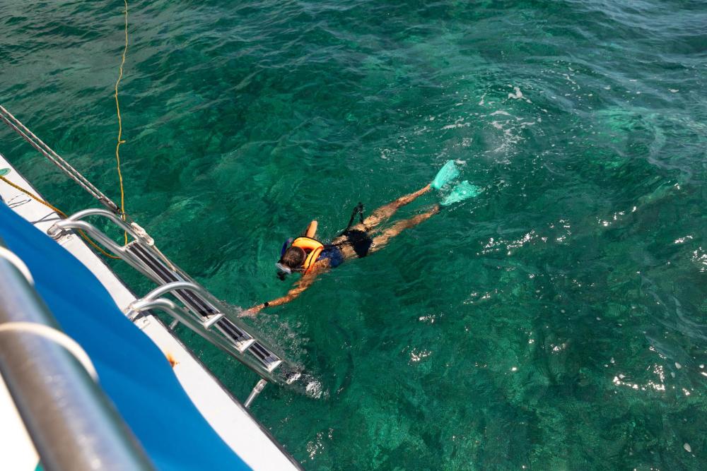 Snorkeler exploring clear turquoise waters beside a boat.