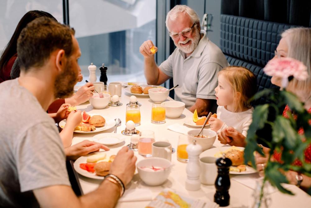A group of adults and a child having breakfast at a table inside an accommodation