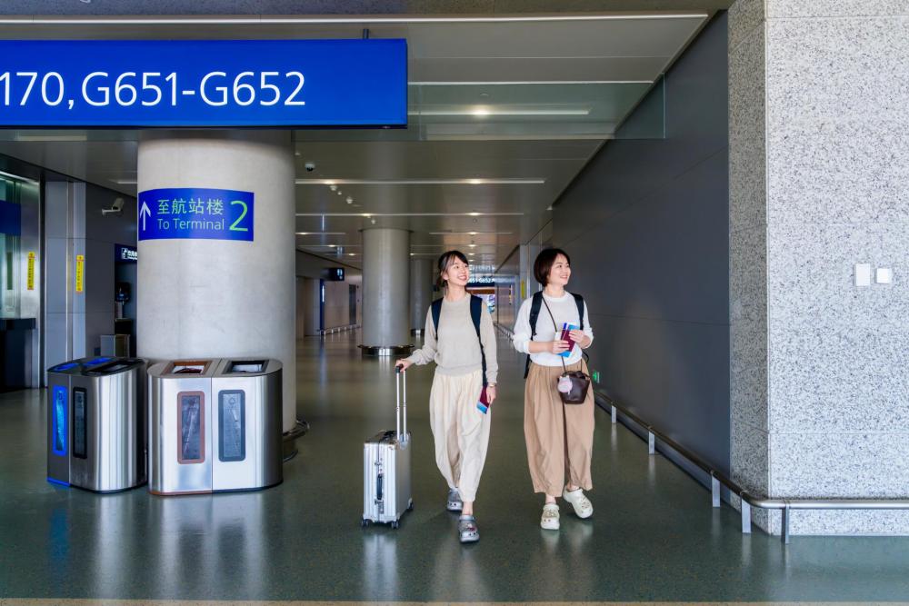 Two travelers holding passports walk through an airport terminal