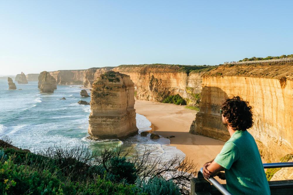 A man looking at the limestone sea stacks of the Twelve Apostles on the Great Ocean Road coast