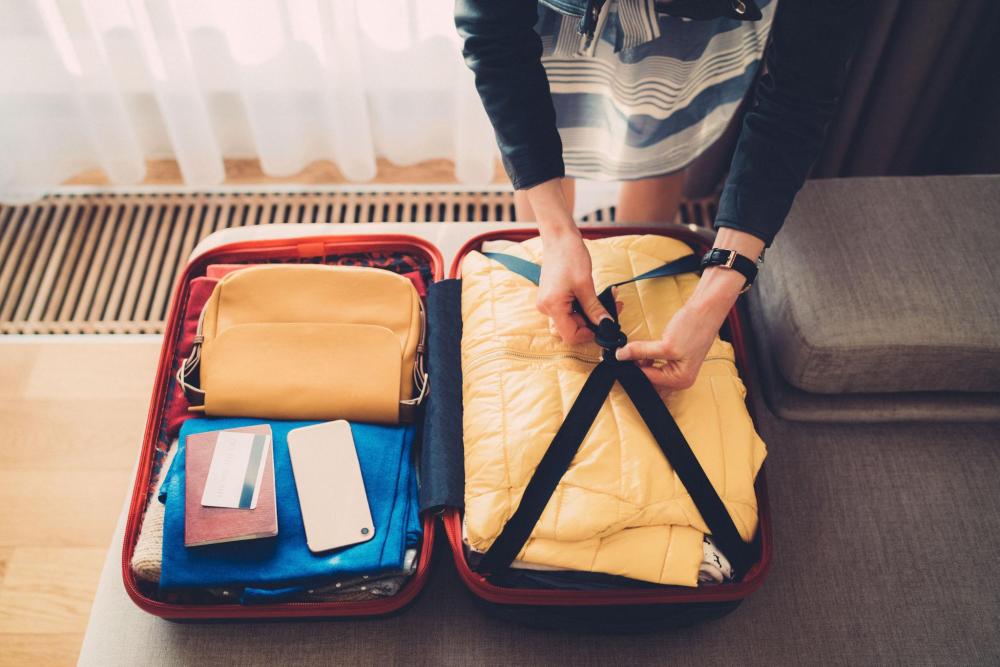 A person adjusting the clips on a suitcase while packing for a journey.