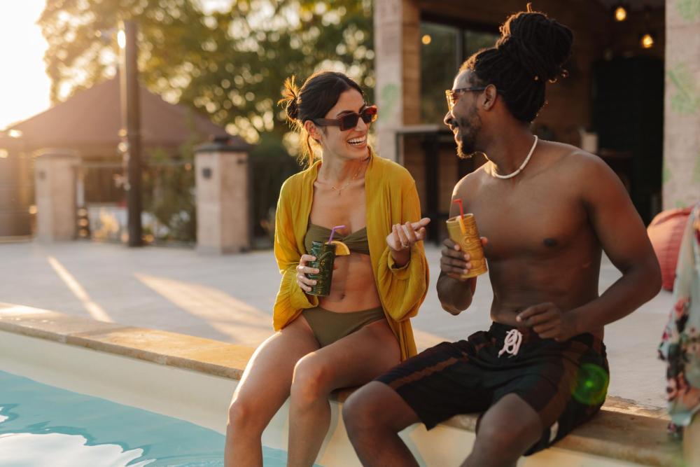 Two people chat while enjoying drinks by the pool