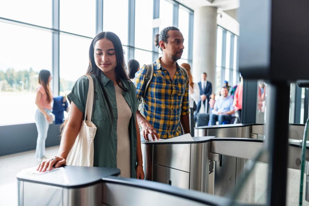 Two travelers scanning their boarding passes at an airport gate