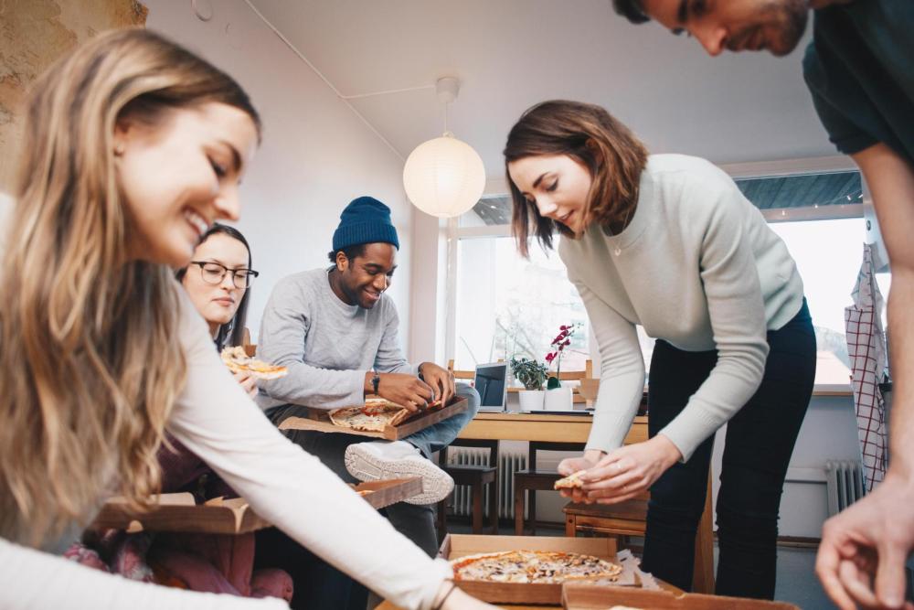 Freunde versammeln sich um einen Tisch, um gemeinsam Pizza zu essen und sich zu unterhalten.