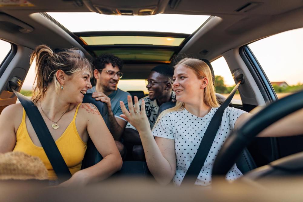 Four adults chat in a car while driving.