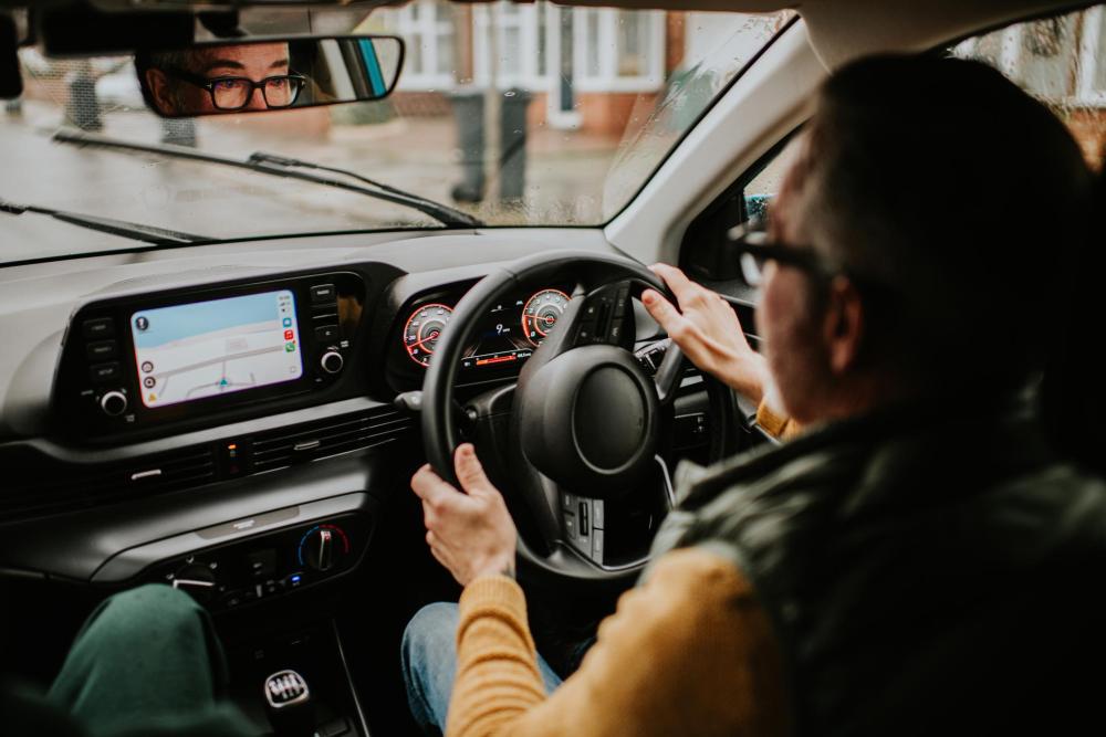 A driver navigates the road using a GPS device on the dashboard