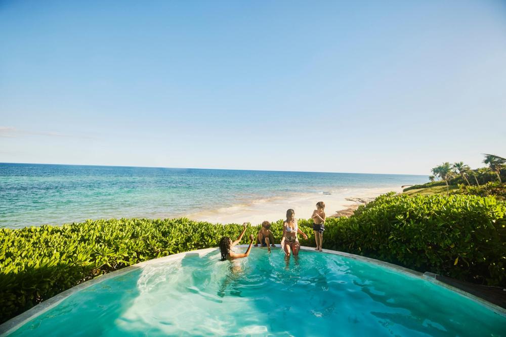 Family enjoying a private pool overlooking the beach and sea on a sunny day 